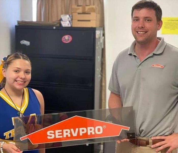 Owner, Left, Tom, with Local High School Cheerleader holding SERVPRO Sign