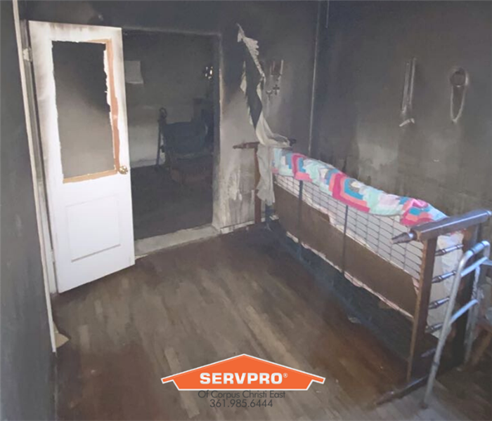 bedroom in home englufed my flames with smoke and soot damage. SERVPRO logo in middle of photo.