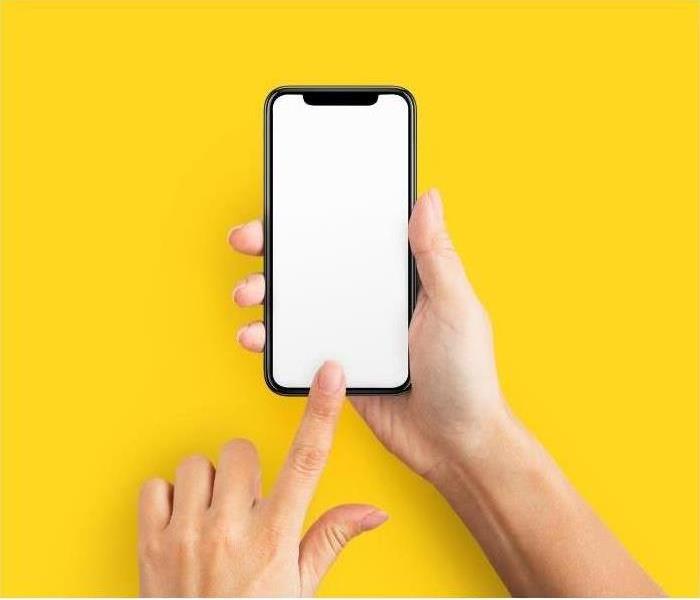 hand holding up a smartphone on a yellow background