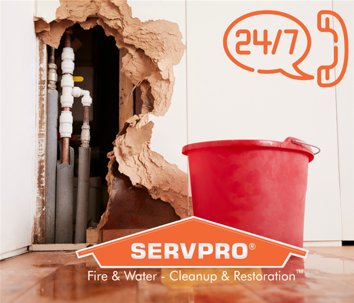 Residential Wall with hole in it after flood and SERVPRO logo 