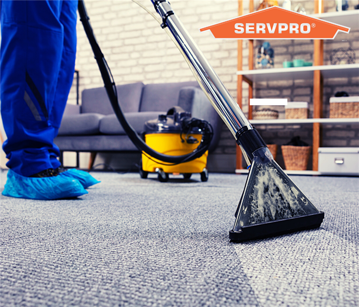 SERVPRO employee cleaning carpet with SERVPRO Logo